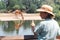 Asian zoology student girl looking at giraffe drinking from lake