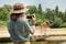 Asian zoology student girl taking photo on smartphone while giraffe drinking from lake