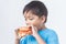 Asianâ€‹ childâ€‹ boyâ€‹ biting andâ€‹ eatingâ€‹ aâ€‹ hamburger.â€‹ Fast food.â€‹ Kidâ€‹ andâ€‹ healthyâ€‹ concept.â€‹ Onâ€‹ white