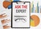 Ask the experts text . Conceptual background with chart ,papers, pen and glasses, business