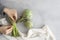 Asparagus bouquet, a couple of artichokes, a light colored napkin on a light wooden background.  Hands making a bow