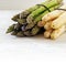 Asparagus, green and white bunch on bright painted wood, background with copy space fades to white, close up