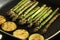 Asparagus and sliced courgette zucchini cooking in a griddle frying pan