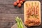 Asparagus wrapped in bacon with tomato on wooden background