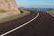 Asphalt coastal road going round cliff edge bend.