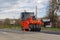 Asphalt compactor roller rolls new asphalt on the highway in the village