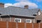 Asphalt . Decorative bitumen shingles on the roof of a brick house. Fence made of corrugated metal