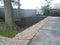 Asphalt driveway with stones and dirt and wood fence