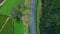 Asphalt highway stretching slopes drone top view. Mountain forest grassy nature