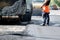 Asphalt machine, worker and steam roller at roadworks renewing city street