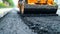 Asphalt paver in action, applying fresh asphalt on a newly constructed road for improved longevity