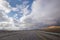 Asphalt road and bright blue sky with fluffy clouds . Empty desert asphalt road from low angle with mountains and clouds on