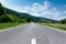 Asphalt road at countryside, forest at roadside, vibrant blue sky