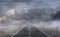 Asphalt road in a desert with dark cloudy sky