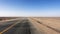 Asphalt road in the desert, strong winds blow up the sands across the road like wave