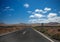 Asphalt road disappearing over the horizon through volcano mountain hillsides. Radar sign. White clouds on a blue sky. Lanzarote