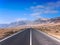 Asphalt road disappearing over the horizon through volcano mountain hillsides. White clouds on a blue sky. Lanzarote