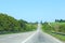 Asphalt road with dividing strip with trees on sides. Travel destination journey