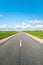 Asphalt road in green fields on blue cloudy sky background