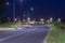 An asphalt road at night, lit by electric lanterns.