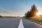 Asphalt road passing through grassland with sunrise