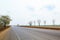 Asphalt road perspective to horizon through cultivated field against cloudy sky