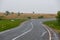 Asphalt road receding into the distance among green fields