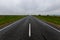 Asphalt road receding into the distance among green fields