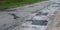 Asphalt road repair of poor quality. Pothole asphalt road repairs. A newly patched roadway in a bad condition