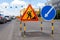 Asphalt road repairs, yellow warning triangle signs about road works and bypass directions