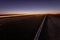 Asphalt road running through the sandy desert at night