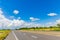 The asphalt road runs along the field and has a beautiful blue sky