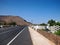 Asphalt road through the southern village. Deep blue sky and volcano hillsides. Lanzarote
