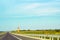 Asphalt road, windmills and driving car in distance