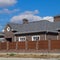 Asphalt shingle. Decorative bitumen shingles on the roof of a brick house. Fence made of corrugated