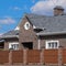 Asphalt shingle. Decorative bitumen shingles on the roof of a brick house. Fence made of corrugated