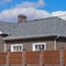 Asphalt shingle. Decorative bitumen shingles on the roof of a brick house. Fence made of corrugated