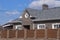 Asphalt shingle. Decorative bitumen shingles on the roof of a brick house. Fence made of corrugated metal.