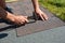 Asphalt shingles installation. Roofer contractor hands installing asphalt shingles on house roofing construction with hammer and