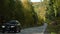 Asphalt Suburban Highway among a dense Autumn Forest on a Sunny Day. Cars pass quickly along the Winding Road. Concept