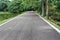 Asphalt Winding road with trees and pond.