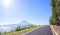 Asphalted road in Azores runs along the grassy shores of the Atlantic Ocean, on a background of of an extinct volcano