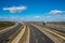 Asphalted road highway goes into bend in distance landscape with blue cloudy sky