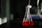 Aspirating a red chemical on a glass conical flask with a pipette in a chemistry lab