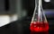 Aspirating a red chemical on a glass conical flask with a pipette in a chemistry lab