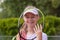 An aspiring smiling girl tennis player looks through a tennis racket.
