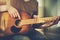 An aspiring young musician plays a tune on an old dilapidated acoustic guitar