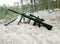 Assault rifle on the background of pine forests and sand