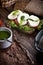 Assembling sandwich with mozzarella, tomatoes, pesto and green salad, on rustic wooden table