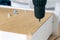 Assembly of furniture, the carpenter screws a self-tapping screw into a drawer with a screwdriver